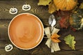 Autumnal table setting for Halloween dinner. Empty plate, cutlery, colored leaves on wooden table. Fall food concept. Royalty Free Stock Photo