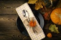 Autumnal table setting for Thanksgiving dinner. Empty plate, cutlery, colored leaves on wooden table. Fall food concept. Royalty Free Stock Photo