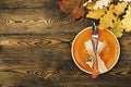 Autumnal table setting for Thanksgiving dinner. Empty plate, cutlery, colored leaves on wooden table. Fall food concept. Royalty Free Stock Photo