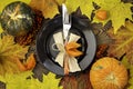 Autumnal table setting for Thanksgiving dinner. Empty plate, cutlery, colored leaves on wooden table. Fall food concept. Royalty Free Stock Photo