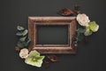 Autumnal-winter composition with vintage frame, dried leaves, bark of trees and berries on dark background. Flat lay, copy space