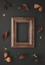 Autumnal-winter composition with vintage frame, dried leaves, bark of trees and berries on dark background. Flat lay, copy space