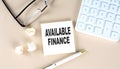 AVAILABLE FINANCE text on sticky with pen ,calculator and glasses on a beige background