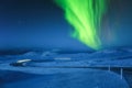 Northern Lights above snow covered icelandic winding road