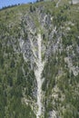 Avalanche track on steep mountainside above a road