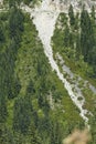 Avalanche track on steep mountainside above a road