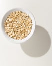 Oat cereal grain. Grains in a bowl. Shadow over white table. Royalty Free Stock Photo