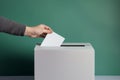 average citizen hand casting a vote paper election ballot in a voting box on a geen background. Caucasian man putting a balloting Royalty Free Stock Photo
