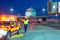 Aviation marshall supervisor meets passenger airplane at the airport at night view. Aircraft is taxiing to the parking place.