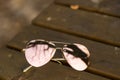 Aviator Sunglasses model with big pink lenses reflecting the sun in a summer day closeup . Selective focus