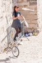 Asian street artist girl juggler juggling with ninepins on one-wheeled bicycle in Old Town of Avignon, France during the Art