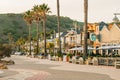 Avila Beach city promenade filled with restaurants, shops, patios, benches, and art. Sunset in the city, dinner time