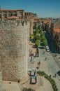 People walking on street in front of tower on the wall of Avila