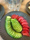 Avocado, cucumbers and tomatoes on a round gray plate