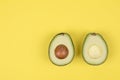 Avocado cut in half on bright yellow background Royalty Free Stock Photo