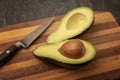 Avocado cut in half on a wooden chopping board