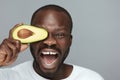 Avocado Facial Treatment. Skin Care With Natural Vitamins. Male African Model Holds Fresh Fruit Near Face.