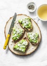 Avocado, goat cheese, grilled ciabatta sandwiches and green tea on light background, top view. Healthy breakfast