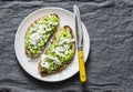 Avocado, goat cheese, grilled ciabatta sandwiches on grey background, top view