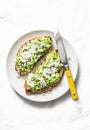 Avocado, goat cheese, grilled ciabatta sandwiches on light background, top view