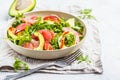 Avocado and grapefruit salad in a white plate on a white background.