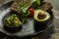 Avocado and guacamole with multigrain bread on a dark plate