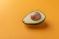 Avocado half with kernel on orange background. Tropical fruit Royalty Free Stock Photo