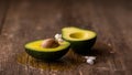 Avocado halves with pit and white flower decoration on a rustic wooden surface. Royalty Free Stock Photo
