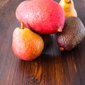 Avocado hass with red pears, ripe mango with water drops on a wooden table close-up, copy space, template Royalty Free Stock Photo