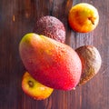 Avocado hass with red pears, ripe mango with water drops on a wooden table close-up, copy space, template Royalty Free Stock Photo