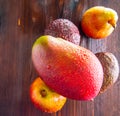 Avocado hass with red pears, ripe mango with water drops on a wooden table close-up, copy space, template Royalty Free Stock Photo