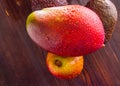 Avocado hass with red pears, ripe mango with water drops on a wooden table close-up, copy space, template Royalty Free Stock Photo