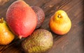 Avocado hass with red pears, ripe mango with water drops on a wooden table close-up, copy space, template Royalty Free Stock Photo