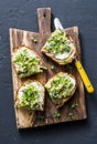 Avocado and labne toast with micro greens on a cutting board, on a dark background, top view. Good fats healthy eating concept. De