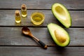 Avocado oil for cosmetology. Sltill lfe with half of fruit and bottles on wooden background