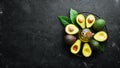 Avocado oil and fresh avocados on a black background. Rustic style. Top view.