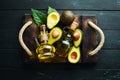 Avocado oil and fresh avocados on a black background. Rustic style. Top view.