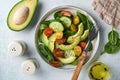 Avocado, red, yellow, black cherry tomato, spinach and cucumber fresh salad with spices pepper and olive oil in grey bowl on grey Royalty Free Stock Photo