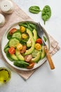 Avocado, red, yellow, black cherry tomato, spinach and cucumber fresh salad with spices pepper and olive oil in grey bowl on grey Royalty Free Stock Photo