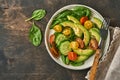 Avocado, red, yellow, black cherry tomato, spinach and cucumber fresh salad with spices pepper and olive oil in grey bowl old wood Royalty Free Stock Photo