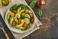 Avocado, red, yellow, black cherry tomato, spinach and cucumber fresh salad with spices pepper and olive oil in grey bowl old wood Royalty Free Stock Photo