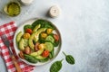 Avocado, red, yellow, black cherry tomato, spinach and cucumber fresh salad with spices pepper and olive oil in grey bowl on grey Royalty Free Stock Photo