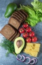 Avocado, sandwiches on whole grain bread with tri-colored tomatoes on rustic baking tray