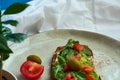 Avocado toast of rye bread with sauce, tomatoes, arugula on large grey plate on blue background. Vegetarian useful breakfast. Royalty Free Stock Photo