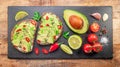 Avocado toasts - bread with avocado slices, pieces of red pepper and sesame on black stone board Royalty Free Stock Photo