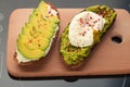 Avocado toasts with cheese and poached egg on a wooden cutting board Royalty Free Stock Photo