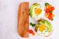 Avocado toasts with eggs and tomatoes, top view on a marble and wood platter Royalty Free Stock Photo