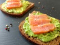 Avocado toasts with slices of smoked salmon and pepper on the dark backround