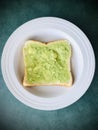 Avocado on white bread in white round plate. Top shot.