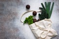 Avocados, celery, kale and leek. Green vegetables in eco shopping bag on the concrete background.